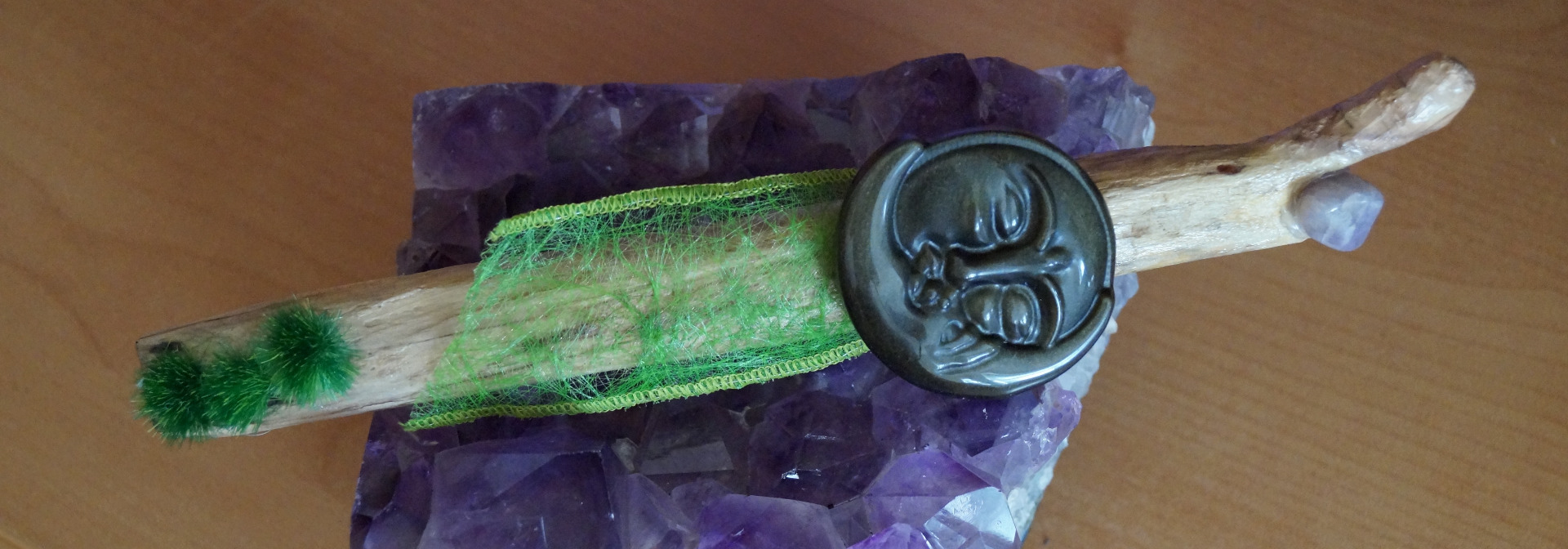Treibholz ca. 21 cm lang, Holz bearbeitet und geschliffen, lackiert, 1 Amethyst ca 1,5 cm, 1 Silberobsidian Sonne/Mond 5cm, grünes Stoffband ca. 10 cm lang, 3 künstliche Grasbüschel zusammen ca. 3,5 cm lang, Wachs